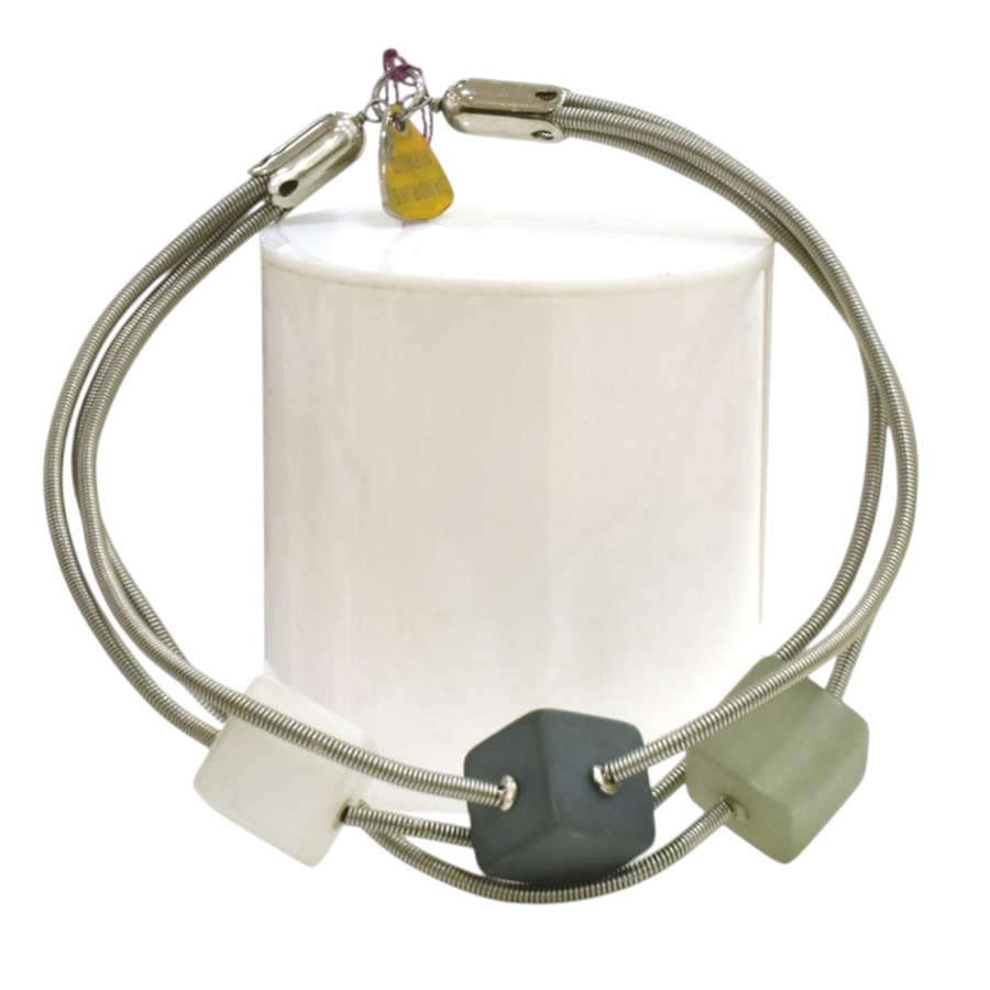 Bracelet TUBE CUBE, no 83, de l'artiste Sandrine Giraud. Couleur gris argent et cubes blanc-gris foncé-olive. Ce bijou marie avec élégance la grâce et l’originalité des lignes.