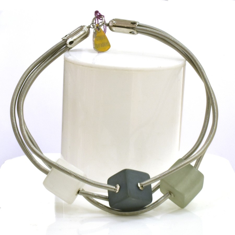 Bracelet TUBE CUBE, no 83, de l'artiste Sandrine Giraud. Couleur gris argent et cubes blanc-gris foncé-olive. Ce bijou marie avec élégance la grâce et l’originalité des lignes.