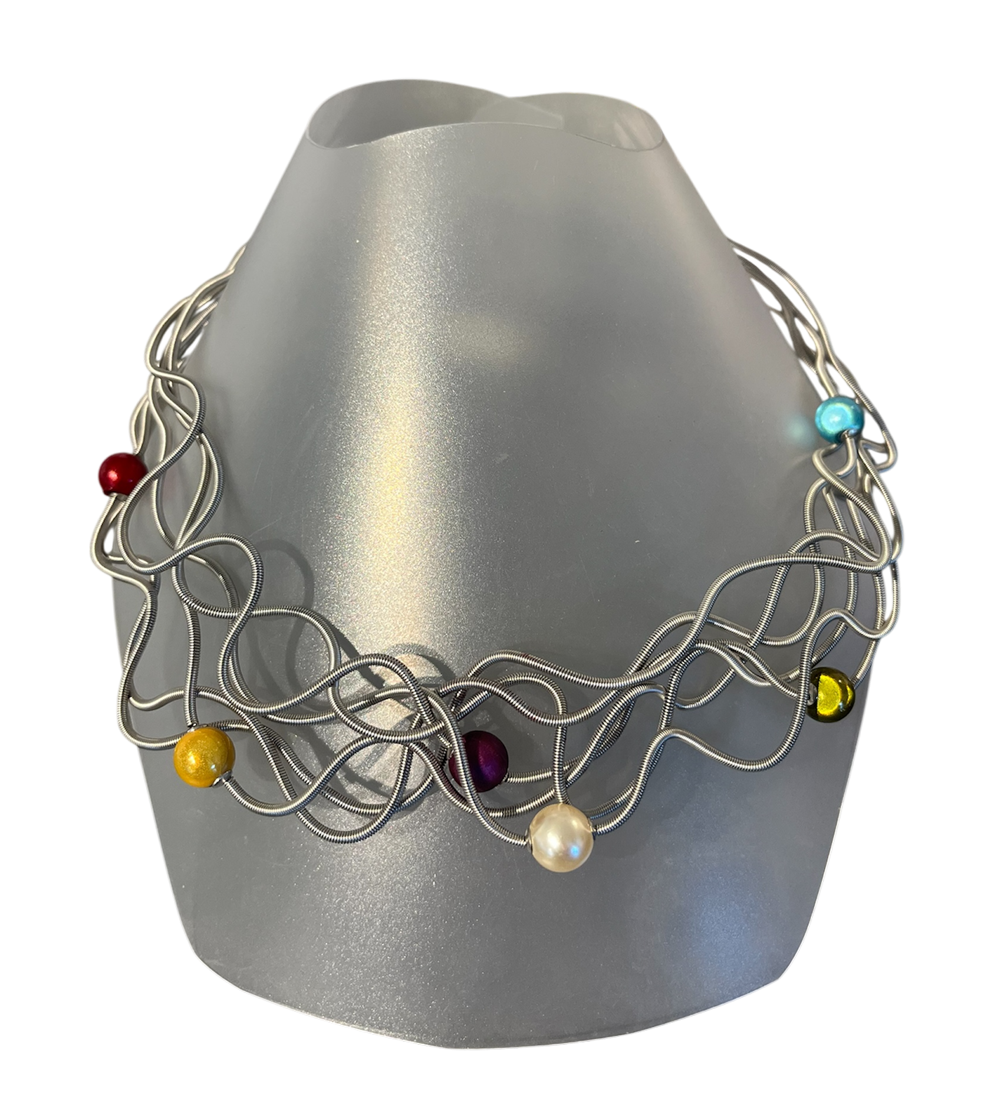 Collier LIANE PERLÉE, no 65, de l'artiste Sandrine Giraud, couleur, gris, perles nacrée, or, rouge et bleu. Ce bijou modulable, toujours original, marie avec élégance la grâce et l’originalité des lignes.