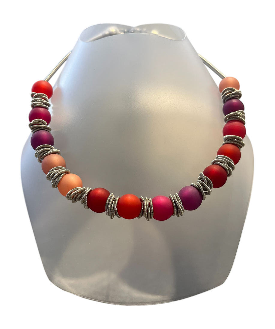 Collier POLARIS, no 154, de l'artiste Sandrine Giraud, couleur, argent, perles roses, rouges, oranges. Ce bijou toujours original, marie avec élégance la grâce et l’originalité des lignes.