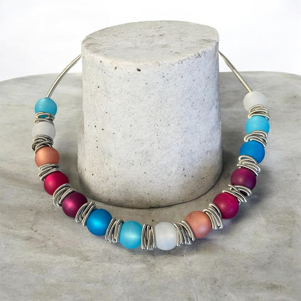 Collier POLARIS, no 184, de l'artiste Sandrine Giraud, couleur, argent, perles bleues, rouges, roses, violettes. Ce bijou toujours original, marie avec élégance la grâce et l’originalité des lignes.