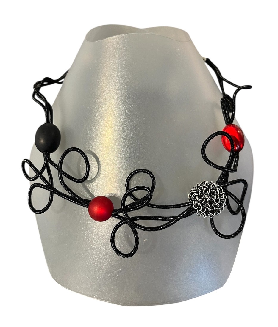 Collier ROSE DES SABLES, no 182, de l'artiste Sandrine Giraud, couleur, noir et perles noires et perles rouges. Ce bijou modulable marie avec élégance la grâce et l’originalité des lignes.