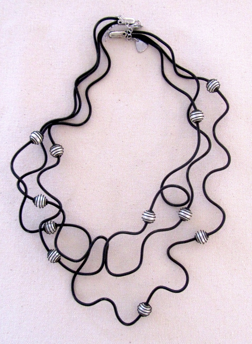 Collier PERLES EN CAGE blanches, no 99, de l'artiste Sandrine Giraud, Ce bijou modulable, toujours original, marie avec élégance la grâce des perles avec l’originalité des lignes résolument contemporaines.