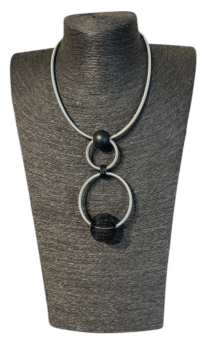 Collier RESSORT DOUBLE ANNEAUX, no 128, de l'artiste Sandrine Giraud, couleur gris argent, noir. Ce bijou marie avec élégance la grâce avec l’originalité des lignes.