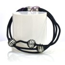 Bracelet PERLE EN CAGE, no 73, de l'artiste Sandrine Giraud. Couleur noir et perles blanches. Ce bijou marie avec élégance la grâce et l’originalité des lignes.