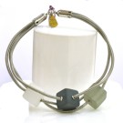 Bracelet TUBE CUBE, no 83, de l'artiste Sandrine Giraud. Couleur gris argent et cubes blanc-gris foncé-olive. Ce bijou marie avec élégance la grâce et l’originalité des lignes.